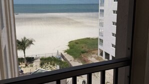 Vista de una playa desde un balcón con piscina y mobiliario de exterior.