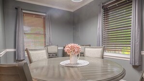 A round dining table with four chairs, a vase of pink flowers, and a textured doily. - Cozy Bungalow Retreat w FirePit & Grill (Columbus)