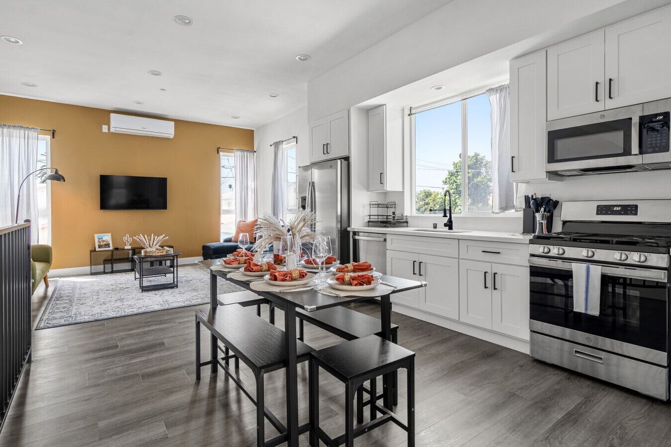 A modern kitchen with white cabinets, a large stove, and a dining area set for a meal.