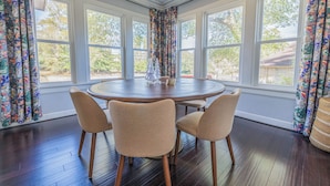 Un coin repas avec une table ronde, quatre chaises et de grandes fenêtres dotées de rideaux.