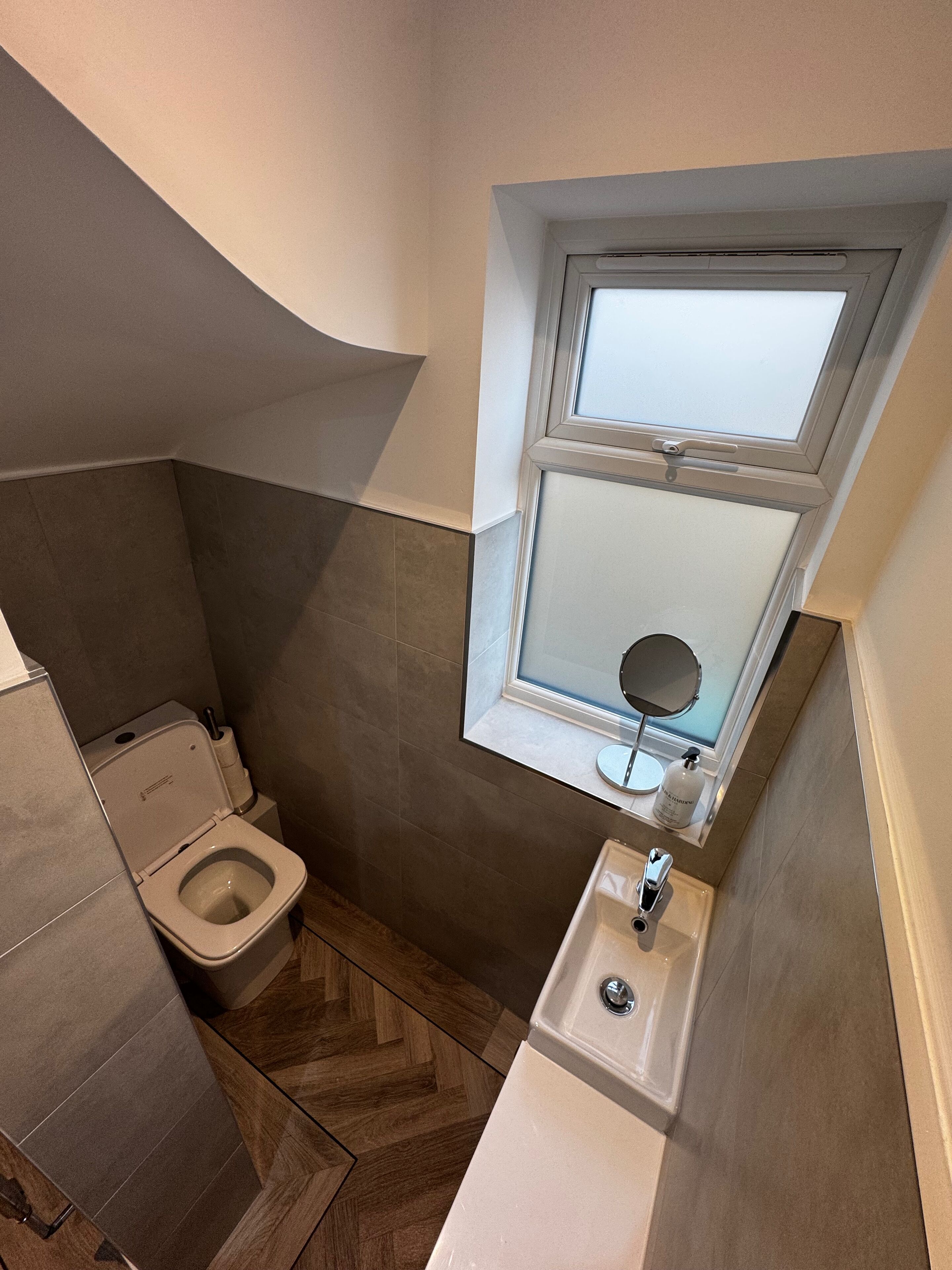 Ein kleines Badezimmer mit Toilette, Waschbecken und einem kleinen Fenster über dem Waschbecken.