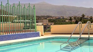 Una piscina con vistas a una montaña y un pueblo al fondo.