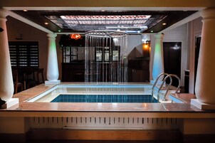 Un área de spa con un jacuzzi, techo con diseño de cuadrícula y una barra de fondo.