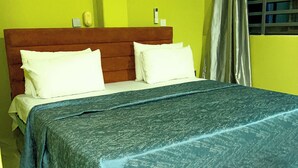 A room with a bed, a wooden headboard, a white air conditioner, and a window with curtains. - Executive Key Hotel (Biseasi)