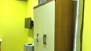 A room with a wardrobe, a television mounted on the wall, and a tiled floor. - Executive Key Hotel (Biseasi)