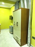 A room with a wardrobe, a television mounted on the wall, and a tiled floor.