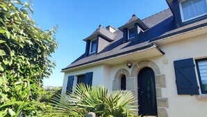 A two-story house with a gabled roof, a stone archway entrance, and a small dormer window.