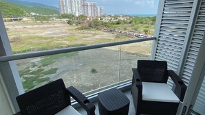 A balcony with two wicker chairs and a small table, overlooking a parking lot and buildings. - Escape to Cabo Tortuga. Apartment near the sea (Santa Marta)