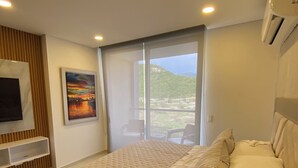 A modern bedroom with a large bed, a TV mounted on the wall, and a painting. - Escape to Cabo Tortuga. Apartment near the sea (Santa Marta)