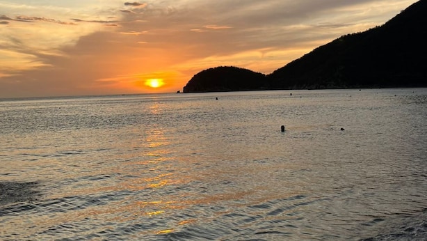 A sunset over a calm sea with distant hills. - Escape to Cabo Tortuga. Apartment near the sea (Santa Marta)