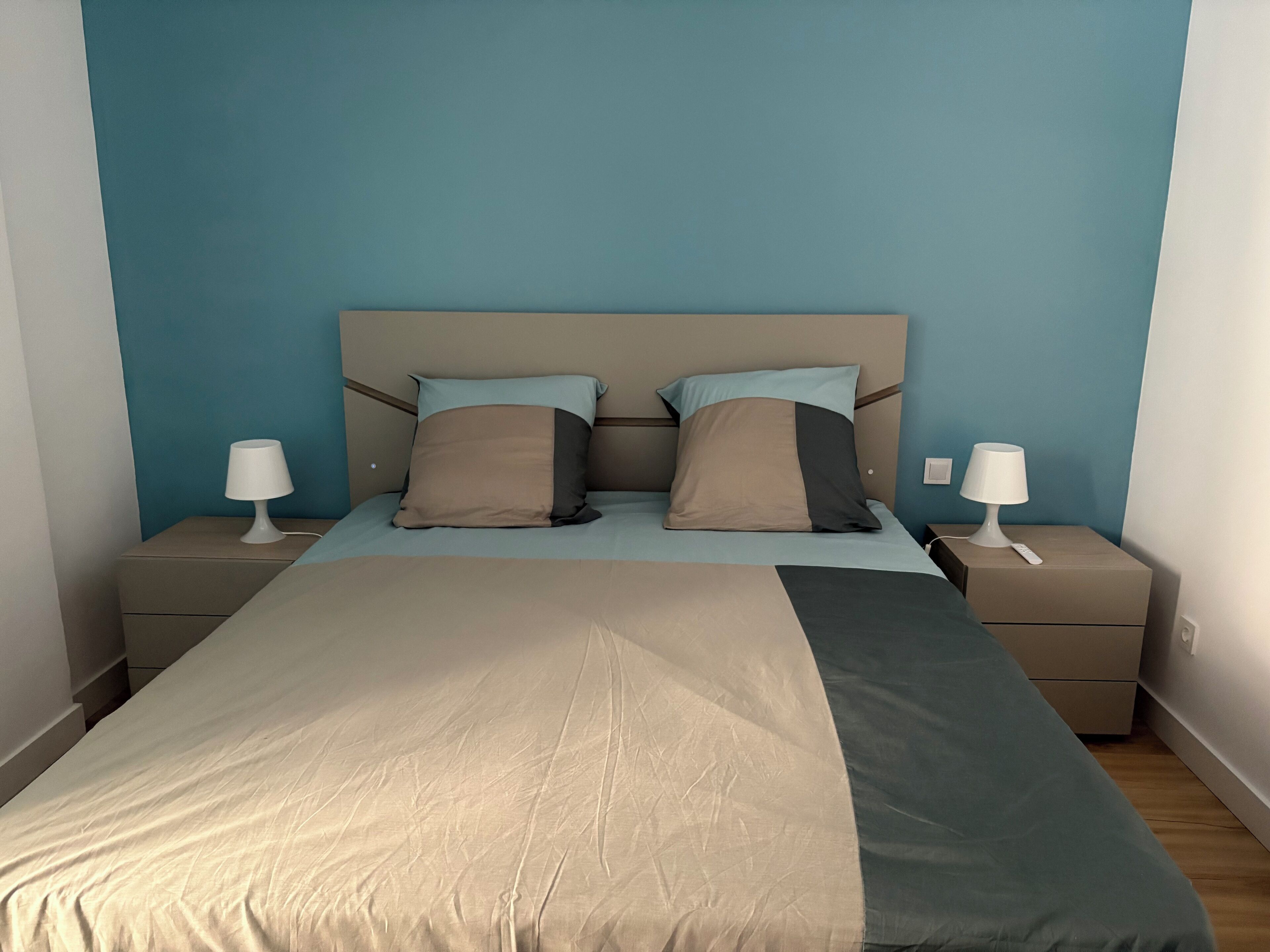 A bedroom with a bed, two bedside tables, and two lamps.
