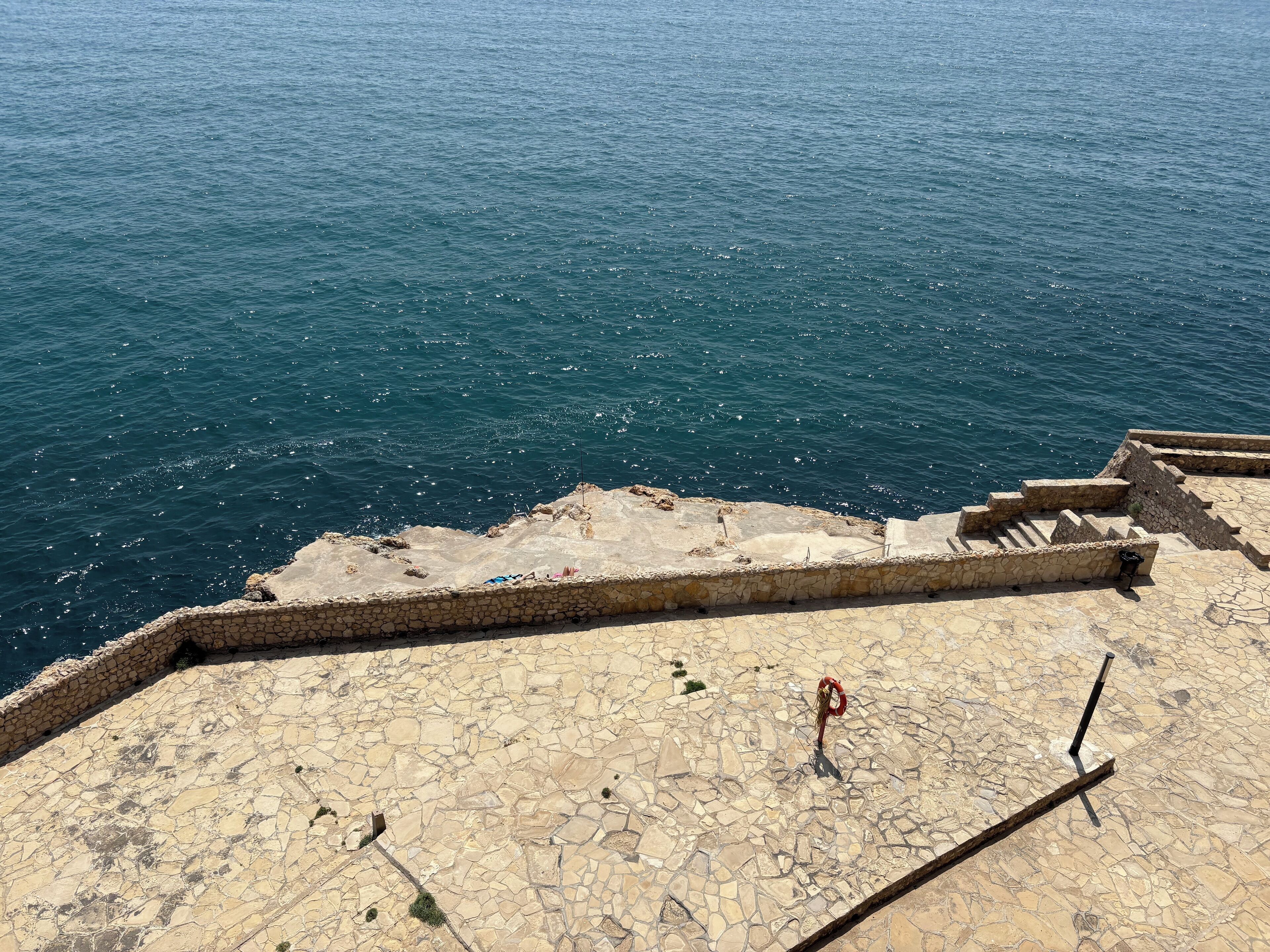 A stone staircase leading down to the sea, with a view of the ocean.