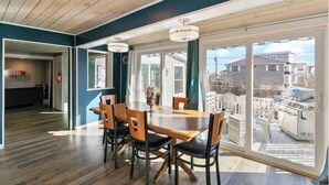 A dining area with a wooden table and chairs, large windows, and a view of the outside. - Spacious 6-bedroom house in serene York, Maine, with Central AC (York)