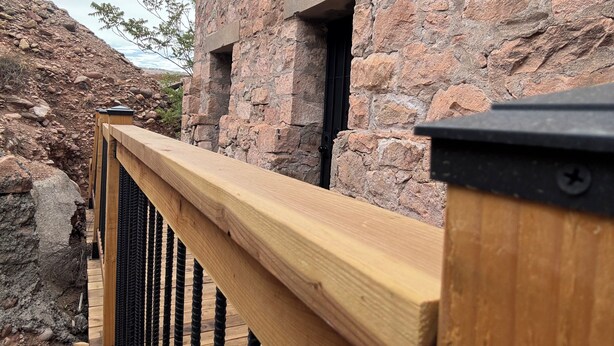 Eine Holzterrasse mit einer Steinmauer im Hintergrund.