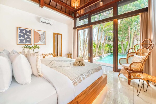 A bedroom with a bed, a chair, a window, and a view of a pool.