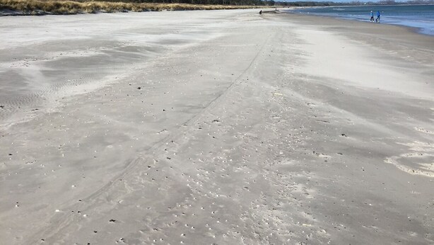 Ein weiter, offener Strand unter blauem Himmel.