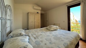 A bedroom with a bed, a wardrobe, and an air conditioning unit.