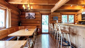 Interior de una cabaña de madera con comedor, barra y asientos.