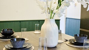 Una mesa de comedor dispuesta con cuencos, platos y vasos de diseño blanco y negro, con un jarrón blanco que contiene flores blancas en el centro.