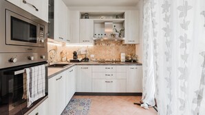 A modern kitchen with white cabinets, a built-in microwave, and a tiled backsplash. - Cozy Antares house recently built super comfortable and accessorized. (Stintino)