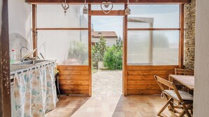 A wooden interior with a kitchen area, a dining table, and a view of the outside. - Cozy Antares house recently built super comfortable and accessorized. (Stintino)