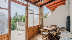 A cozy patio area with a wooden table and chairs, a stone floor, and a view of greenery outside. - Cozy Antares house recently built super comfortable and accessorized. (Stintino)