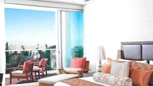 Una habitación de hotel con una cama grande, un balcón con sillas y vistas al exterior.
