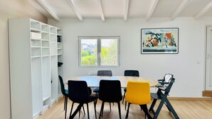 A dining area with a round table, chairs, a white shelving unit, and a skylight.