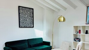 A modern living room with a green sofa, two armchairs, a coffee table, a floor lamp, and a bookshelf.