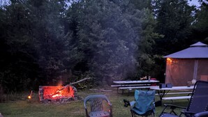 Ein Garten mit Steinkamin, Gartenmöbeln und einem überdachten Bereich.