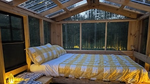 Ein gemütliches Holzhaus mit einem Bett, einer Bank und einem Oberlicht.