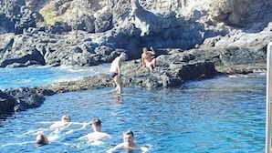 A swimming pool with clear blue water surrounded by rocky terrain. - Surf Harbour  (Granadilla de Abona)