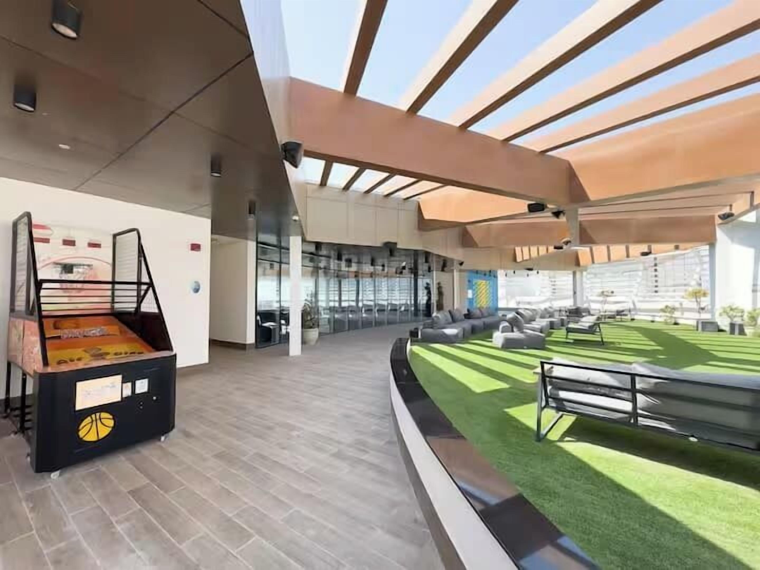 A modern building with a basketball court, seating area, and a covered outdoor space.