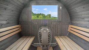 Sala de sauna con bancos de madera, un ventanal grande y un ventilador central.