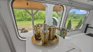 Un área de cocina con vistas a la vegetación por la ventana, una encimera blanca y una bandeja con utensilios de cocina.