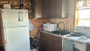 Une cuisine de taille réduite, avec des meubles en bois, un réfrigérateur blanc, un four à micro-ondes, une cuisinière et un évier.