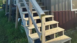 Un escalier en bois mène à un bâtiment en métal doté d’une fenêtre et d’une porte.