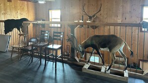 Un intérieur rustique avec des murs en bois, un coin repas avec des chaises et des têtes d’animaux fixées au mur.