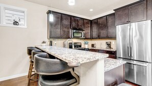 Una cocina moderna con armarios de madera oscura, electrodomésticos de acero inoxidable y encimera de mármol.