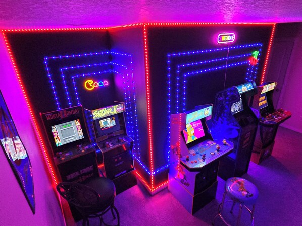 Um salão de jogos com luzes de neon e várias máquinas de jogo.