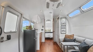 Un espacio interior compacto con kitchenette, una cama y una zona de estar.