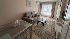 A living room with a sofa, coffee table, and a TV. - Romantic flat 3 min from the beach and 1 min from golf course (VC)