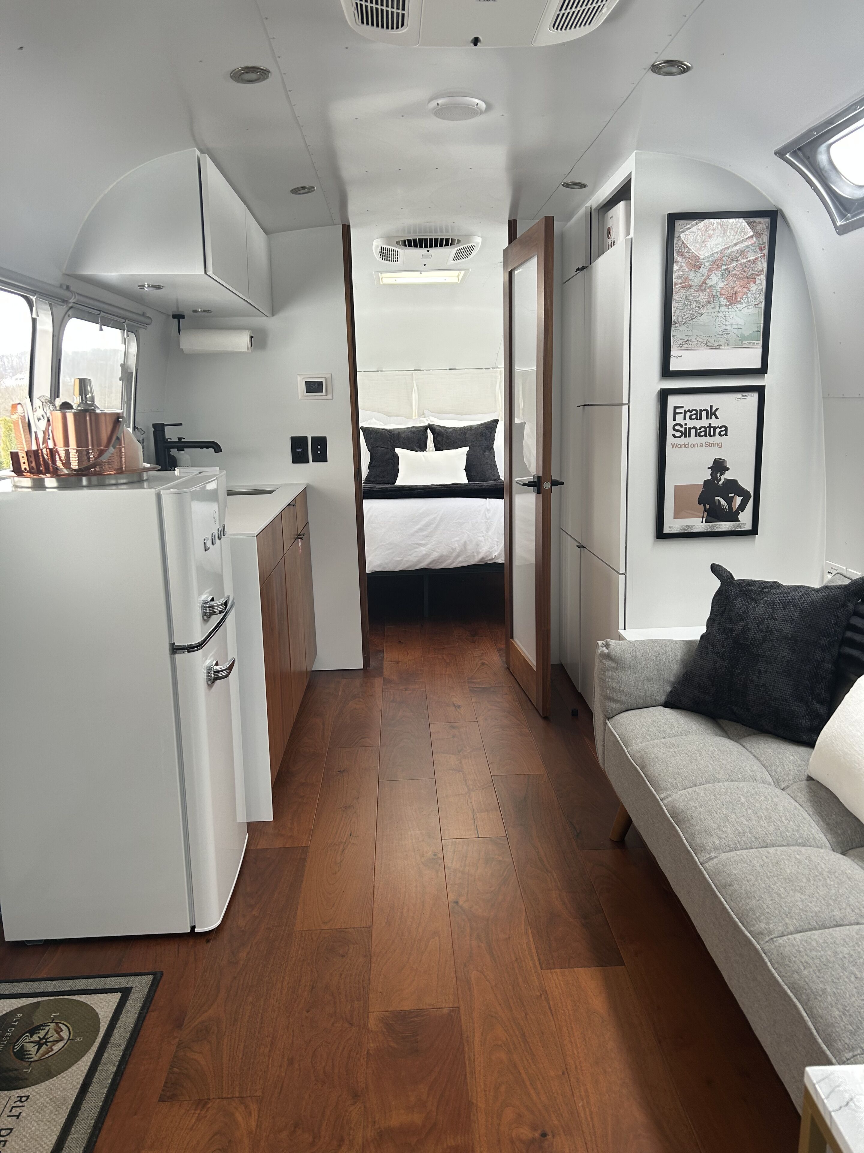 Un intérieur moderne et compact comprenant un coin cuisine, un lit et un espace salon.