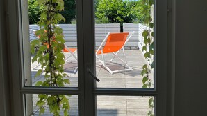 Una ventana con vistas a mesas al aire libre y follaje.