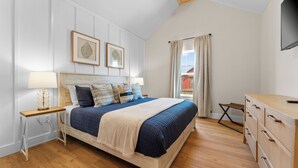 A bedroom with a bed, bedside table, dresser, and a TV on the wall. - Modern Family Lodge 1 Mi to Silver Dollar City, Indoor Pool, Hot Tub, Arcade, EV (Branson)