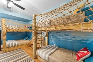 A bunk bed room with a netted canopy, a wooden ladder, and a blue wall.