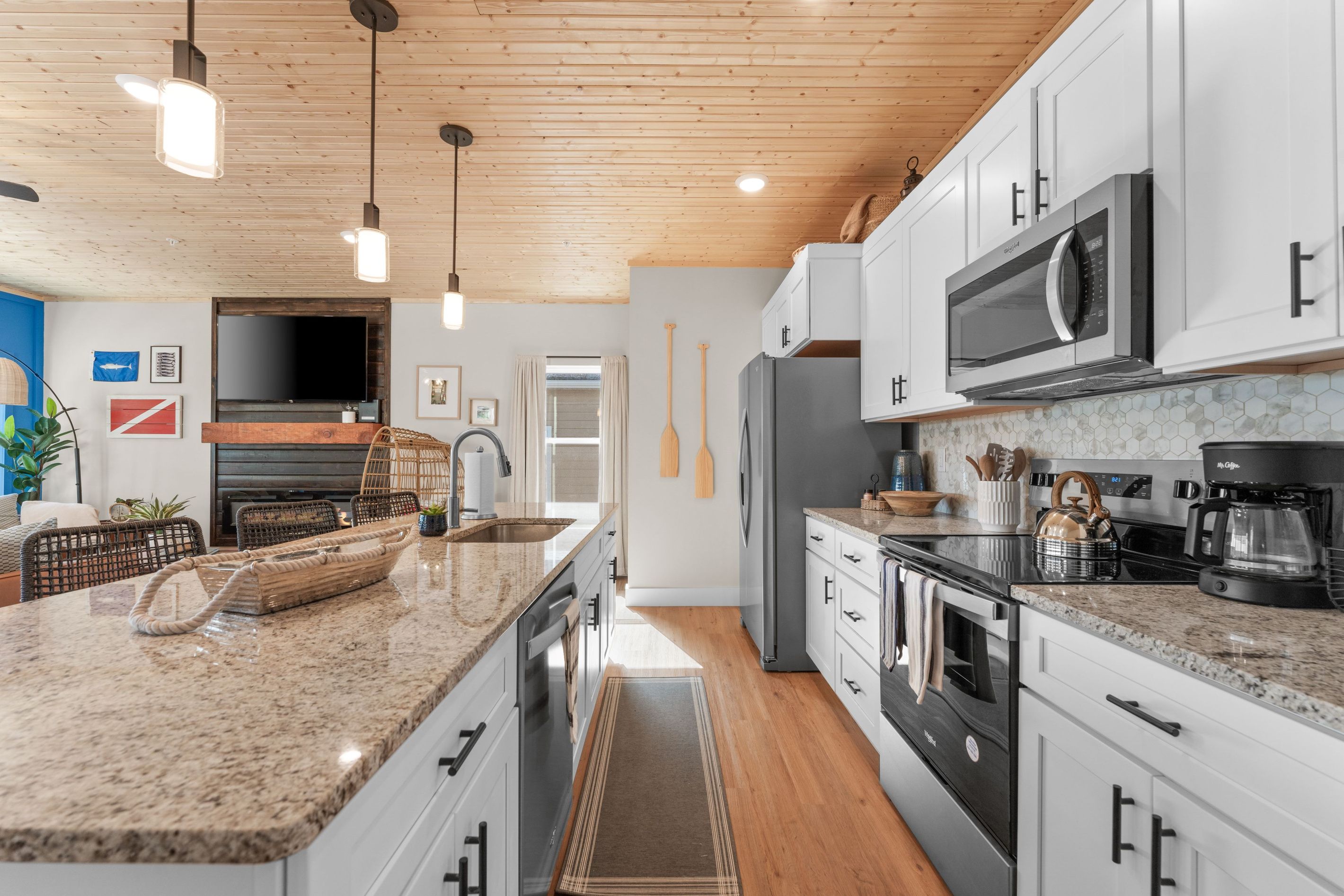 Une cuisine moderne dotée d’un îlot central, d’appareils électroménagers en acier inoxydable et d’un plafond en bois.