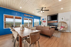 A spacious room with a wooden ceiling, a large dining table with wicker chairs, a leather sofa, and a television mounted on the wall. - Modern Family Lodge 1 Mi to Silver Dollar City, Indoor Pool, Hot Tub, Arcade, EV (Branson)