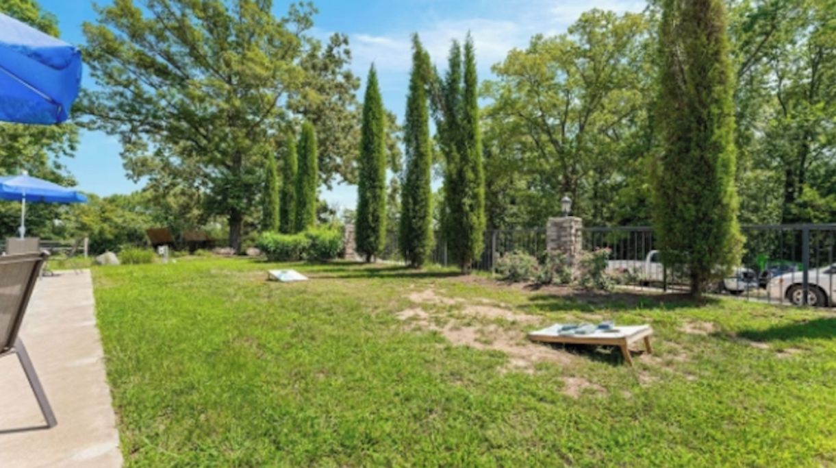 A well-maintained outdoor area with a lawn, a stone structure, and a blue umbrella.