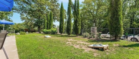 A well-maintained outdoor area with a lawn, a stone structure, and a blue umbrella.